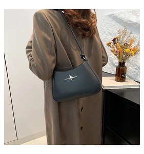 Vista detallada del bolso bajo el brazo negro minimalista con un detalle de estrella plateada