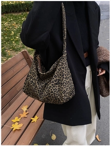 Detail of large leopard print hobo bag with thick fabric texture in autumn park setting