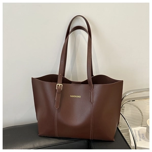 Détail de la texture cuir marron foncé de haute qualité et du logo doré sur le sac cabas