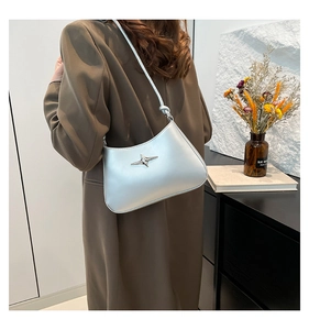 Bolso plateado de hombro con logotipo de estrella metálica llevado por una modelo real