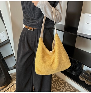 Close-up of yellow fuzzy plush tote bag with smooth white strap in a stylish indoor setting