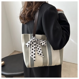 Detailed shot of striped canvas tote bag with a polka dot bow on model's shoulder