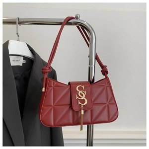 Close-up of quilted deep red shoulder bag with gold metal buckle and tassel detail