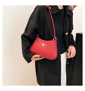 Detalle de bolso hobo rojo con adorno de estrella plateada y correa con nudo