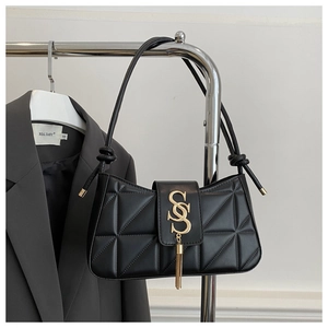 Detail of black quilted shoulder bag with gold letter charms and fringe tassel decoration