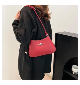 Detalle del bolso de hombro en cuero rojo con estrella plateada y correa con nudo