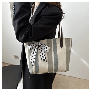 Détail d'un sac cabas en toile rayée avec un foulard à pois et des poignées en cuir chic