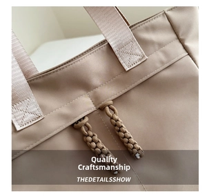 Detailed close-up of double-stitched reinforced handles and woven drawstring on beige tote bag