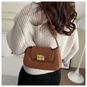 Detail of caramel puffy saddle bag with gold square buckle and decorative knotted strap