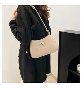 Detalle del bolso de hombro en piel sintética beige con adorno de estrella metálica plateada