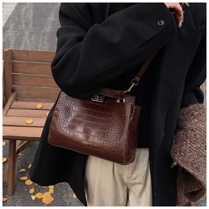 Détail du sac à main marron avec motif crocodile et élégant fermoir rotatif en métal doré