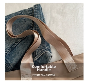 Detail view of the comfortable wide woven strap and stitching on the beige tote bag