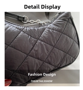 Close-up of black quilted nylon texture with classic diamond pattern and silver chain detail