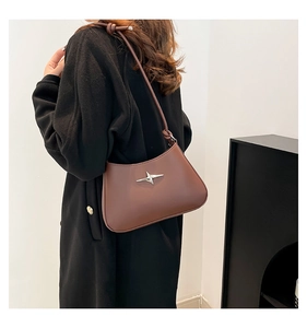 Detalle de bolso de hombro en cuero marrón oscuro con estrella de plata y nudo