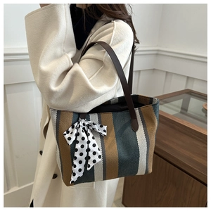 Détail d'un cabas en toile rayée avec foulard en soie porté avec un manteau d'hiver