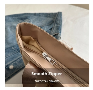 Detailed macro view of the smooth silver zipper closure on a khaki nylon tote bag