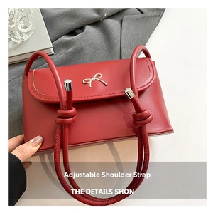 Detail of red leather crossbody bag with golden bow and adjustable knotted shoulder strap
