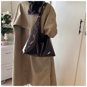 Dark brown high-gloss leather tote bag shown in a warm winter lifestyle setting