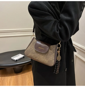 Dettaglio della borsa baguette in pelle bicolore marrone con ciondolo da tennis