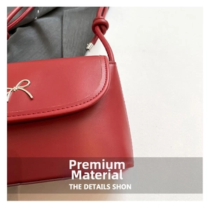 Detail of red crossbody bag with golden bow clasp and high-quality PU leather texture