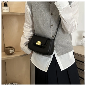 Detail of minimalist black leather baguette bag with a premium golden square metal lock
