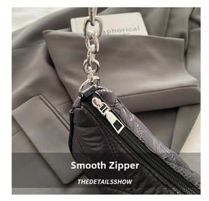 Detail of silver zipper and quilted diamond pattern on black nylon shoulder bag