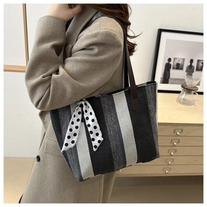 Sac fourre-tout chic en toile à rayures porté par un mannequin en intérieur