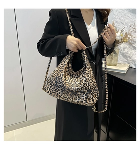 Detail of leopard print hobo bag with dual straps worn over a black stylish blazer