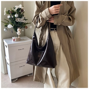 Glossy chocolate brown leather hobo bag shown being worn in a warm lifestyle setting