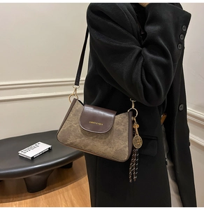 Dettaglio della borsa hobo in pelle retrò con ciondolo a racchetta e nappa in corda