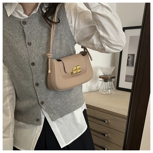 Close-up of the elegant golden butterfly clasp on the beige leather French saddle bag