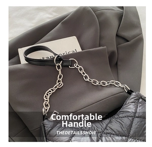 Detail of black quilted shoulder bag featuring silver metal chain and nylon texture