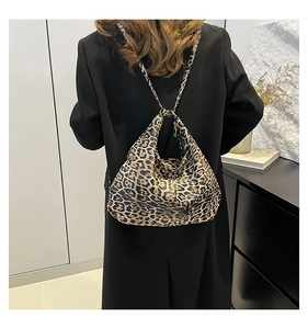 Detail of soft leopard print tote bag styled with a long black coat for a trendy look