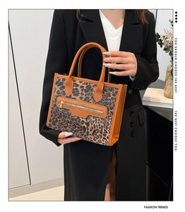 Close-up of leopard print tote bag with brown leather handles and golden zipper details