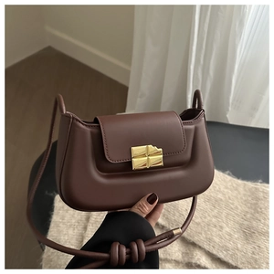Details der minimalistischen schokobraunen Ledertasche mit Goldschnalle und Knotengurt