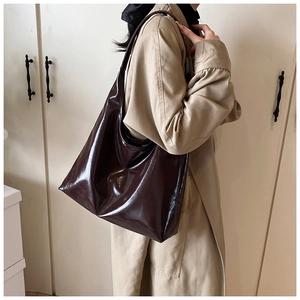 Detail view of large dark brown hobo bag with glossy finish and single shoulder strap