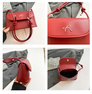 Detail view of red faux leather handbag with golden bow buckle and knotted strap