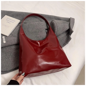 Detail shot of vintage dark red glossy faux leather tote bag on a wool coat background