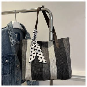Detail of striped canvas tote with brown leather handles and polka dot silk scarf accessory