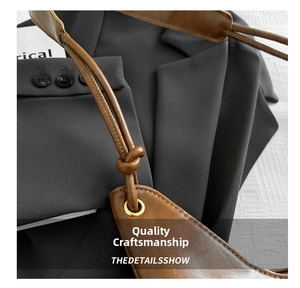 Detail of brown leather tote bag showing knotted shoulder strap and gold eyelet hardware