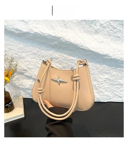 Detalle de bolso caqui con hebilla metálica de estrella y correa de cuerda anudada