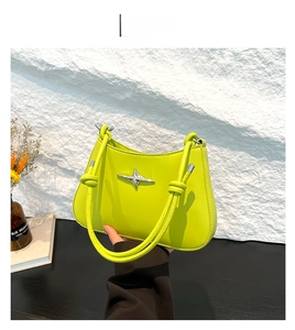 Detalle de bolso de hombro verde neón con estrella plateada y mango anudado