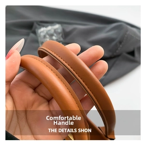 Close-up of comfortable reinforced brown leather handles with neat stitching on tote bag