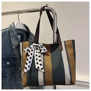 Detail of striped canvas tote with polka dot bow and leather strap on a hanger