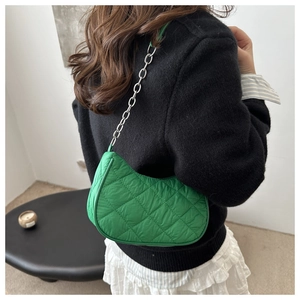 Green quilted half-moon shoulder bag with thick silver chain on black sweater