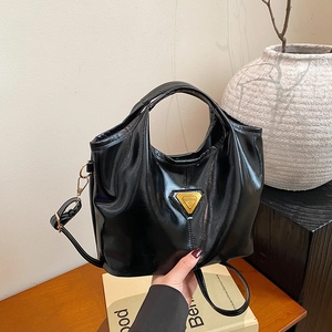 Glossy black patent leather tote bag with gold triangle hardware and crossbody strap
