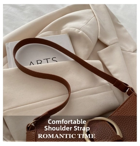 Detail of brown litchi pattern leather bag with wide strap and large gold metal buckle