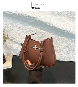 Detalle de un bolso de hombro marrón con hebilla de estrella plateada y correa con nudo
