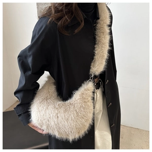Detailed close-up of a plush off-white crescent crossbody bag with a fuzzy shoulder strap