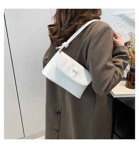 Détail du sac sous l'épaule blanc minimaliste avec nœud argenté et bandoulière nouée